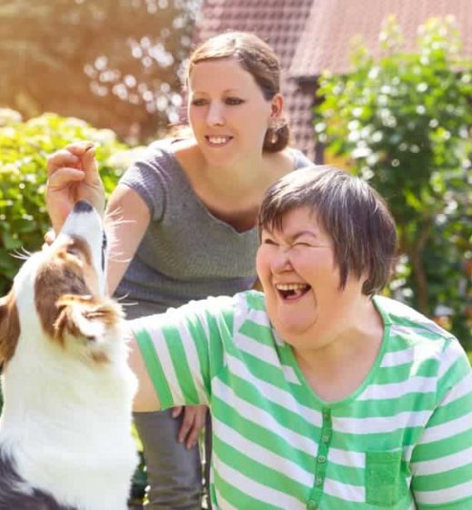 Woman smiling while playing with a dog — Disability Support in Wollongong, NSW