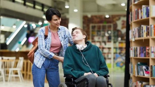 Guy wearing green sweatshirt sitting on wheelchair — Disability Support in Wollongong, NSW